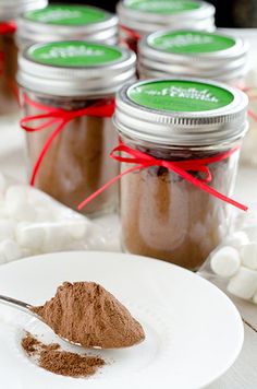 there is a spoon full of cocoa powder and marshmallows on the table