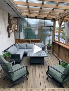 an outdoor living area with couches, chairs and tables on a wooden deck surrounded by plants