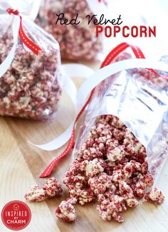 a bag filled with red and white popcorn sitting on top of a wooden table next to another bag