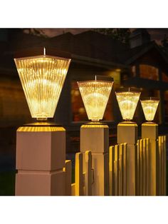 three lights that are sitting on top of some poles in front of a house at night