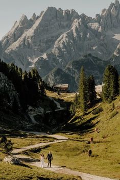 two people walking down a path in the mountains