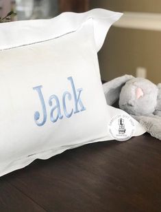 a white pillow with the word jack on it next to a stuffed animal