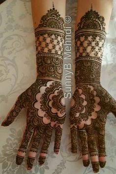 two hands with henna tattoos on them, one is showing off the intricate design