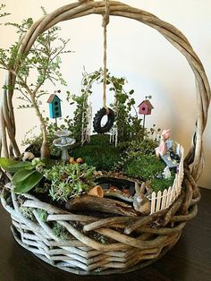 a wicker basket filled with plants and miniature figurines on top of a wooden table