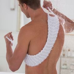 a shirtless man is washing his hair in the shower