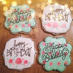 four decorated cookies sitting on top of a wooden table