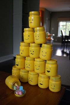 a stack of yellow jars with faces painted on them sitting on a table in front of a dining room