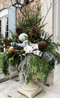 a planter filled with pine cones and evergreens on the side of a building