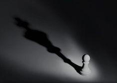 the shadow of a chess pawn on a black and white background is cast by an object