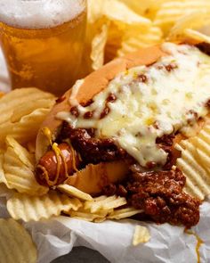 a chili cheese dog with chips and a beer