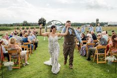 a bride and groom walking down the aisle after their wedding ceremony in an open field