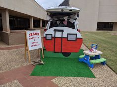 a car that is parked in front of a building with a sign on the grass