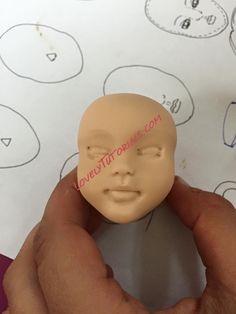 a person holding a plastic head in front of a paper with an image of a child's face on it