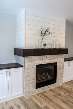 a fireplace in a room with white cabinets and wood flooring on the side wall