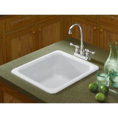 a white sink sitting on top of a counter next to green bottles and glass vases