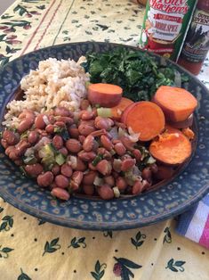 a blue plate topped with beans, rice and carrots on top of a table