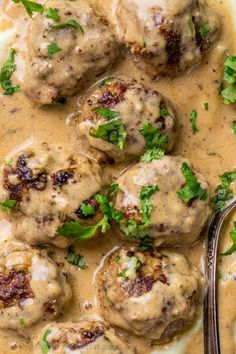 a skillet filled with meatballs covered in gravy and garnished with parsley