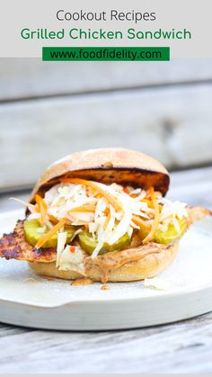 a grilled chicken sandwich with coleslaw and pickles on a white plate