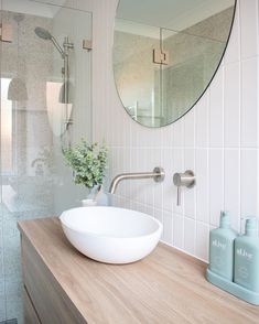 a white bowl sink sitting on top of a wooden counter next to a bathroom mirror