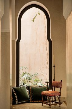 a chair sitting in the middle of a room with an arched doorway and window above it