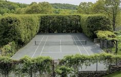 an aerial view of a tennis court surrounded by trees and bushes in the middle of a park