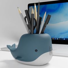 a blue whale pen holder with pencils and markers in front of a laptop