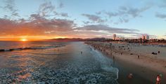 people are walking on the beach at sunset