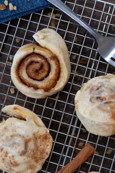 three cinnamon rolls sitting on top of a cooling rack next to a fork and spoon