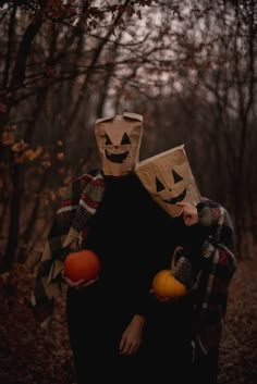 a person with two bags on their head holding pumpkins