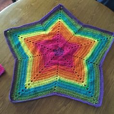 a colorful crocheted square sitting on top of a wooden table