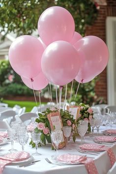 a table set up with pink balloons and place settings