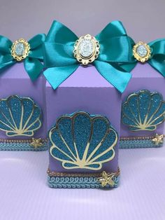 three purple boxes with blue and gold designs on them, one has a green bow