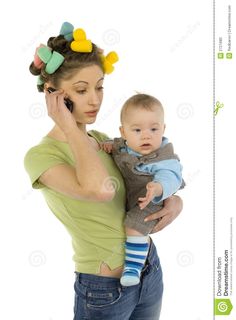 a woman is holding a baby and talking on the phone stock photo's enlarge