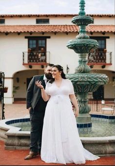 a bride and groom standing in front of a fountain