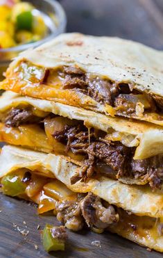 three quesadillas stacked on top of each other with meat, cheese and peppers