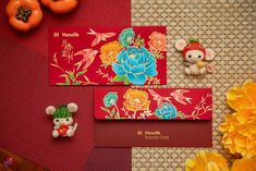 two red envelopes decorated with flowers and small figurines