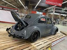 an old car is being worked on in a garage with wooden pallets around it