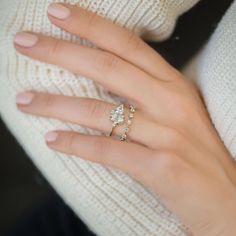 a woman's hand wearing a white sweater and gold ring with three diamonds on it