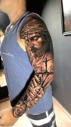 a man with a tattoo on his arm holding a cross and jesus's head