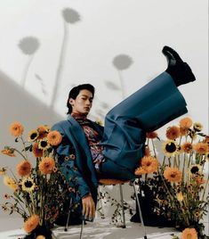 a man sitting on top of a chair in front of some flowers and sunflowers