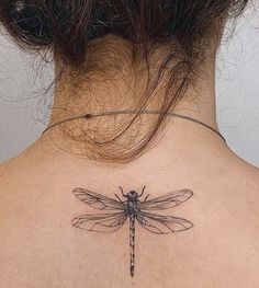 the back of a woman's neck with a dragonfly tattoo on it