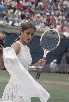 a woman holding a tennis racquet on top of a tennis court in front of a crowd