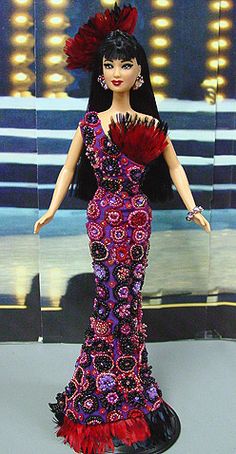 a barbie doll wearing a purple and red dress with feathers on it's head