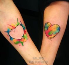 two people with tattoos on their arms holding hands and one has a heart painted on it