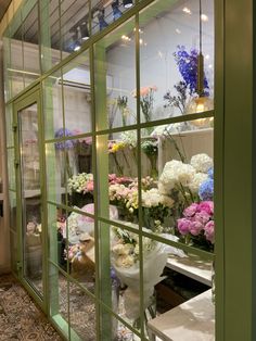 a bunch of flowers that are sitting in a glass case on the ground near a wall