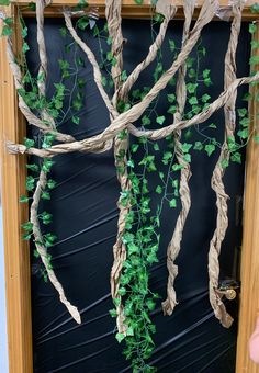 a wooden frame with vines and leaves hanging from it's sides in front of a black wall