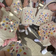 a group of people standing around each other with bags on their backs and letters all over them