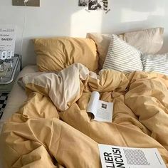 an unmade bed with yellow sheets and books on the bottom shelf next to it