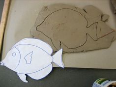 paper cut out of the shape of a fish next to a piece of construction paper