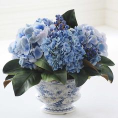 a blue and white vase with some flowers in it